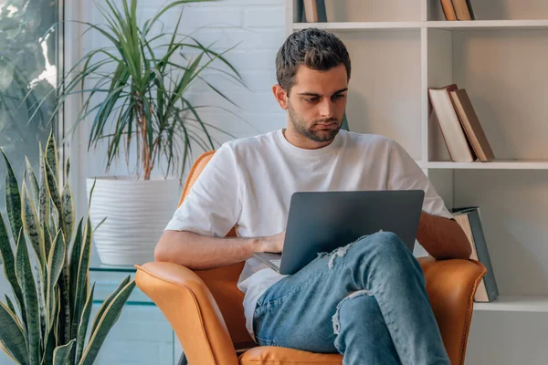 stock image young man at home with laptop on sofa