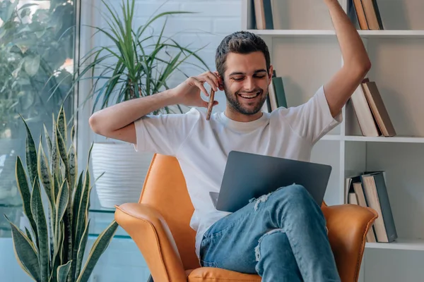 Bilgisayarlı ve cep telefonlu genç adam başarısını ve neşesini ifade ediyor