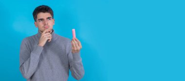 Elinde tebeşirle ve düşünceli genç bir adam veya öğrenci.