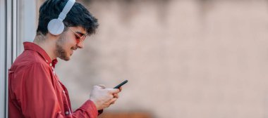 Kulaklıklı ve cep telefonlu genç adam.