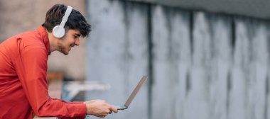 Kulaklık ve dizüstü bilgisayarı olan genç bir adam.