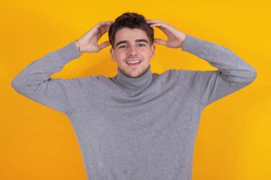 Kolları havada gülümseyen genç adam arka planda tek başına.