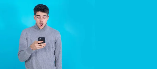 Έκπληκτος Νεαρός Άνδρας Κινητό Τηλέφωνο Smartphone Απομονώνονται Μπλε Φόντο — Φωτογραφία Αρχείου