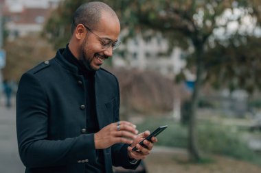 Sokaktaki iş adamı cep telefonuna ya da akıllı telefona bakıyor.