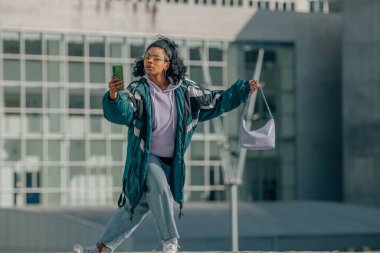 Klasik şehir kızı cep telefonuna bakarak dans ediyor.