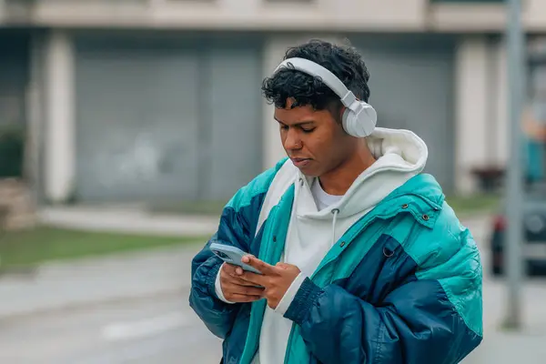 young man with mobile phone and headphones in the street