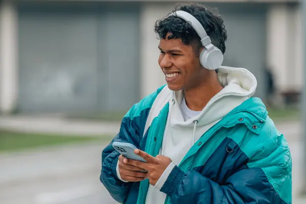 young man with mobile phone and headphones in the street