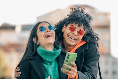 Sokaktaki arkadaşlar cep telefonuna bakıyor.