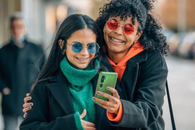 Sokaktaki arkadaşlar cep telefonuna bakıyor.