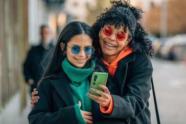 Sokaktaki arkadaşlar cep telefonuna bakıyor.
