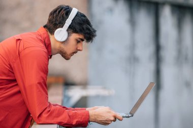 Kulaklık ve dizüstü bilgisayarı olan genç bir adam.