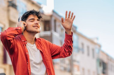 Genç adam kulaklıkla müzik dinlemekten hoşlanıyor.