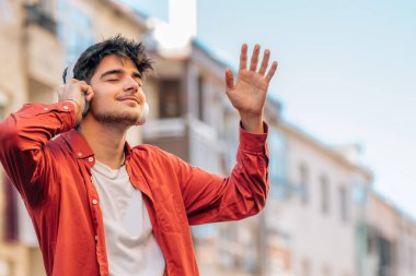 Genç adam kulaklıkla müzik dinlemekten hoşlanıyor.