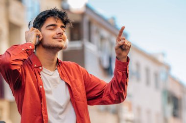 Genç adam kulaklıkla müzik dinlemekten hoşlanıyor.