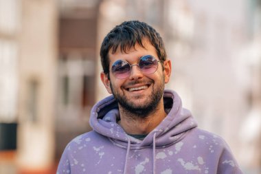 Güneş gözlüklü ve sakallı genç bir adamın portresi.