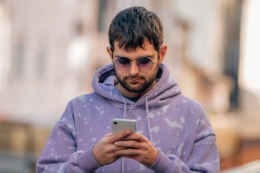 Sokakta cep telefonu ya da akıllı telefonu olan genç adam.