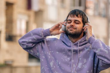 Kulaklıklı genç adam müzik dinliyor ve eğleniyor.