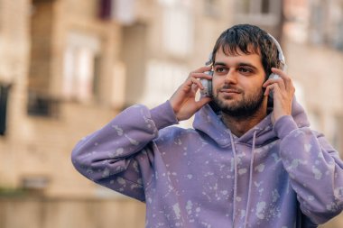 young man enjoying listening to music with headphones outdoors