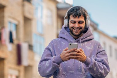 urban young man with mobile phone or smartphone and earphones in the street