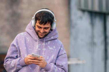 urban young man with mobile phone or smartphone and earphones in the street