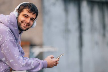 urban young man with mobile phone or smartphone and earphones in the street