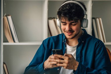 young male at home with headphones looking at mobile phone or smartphone