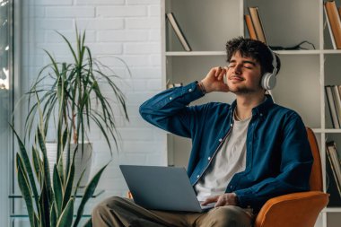 young man at home with laptop and headphones