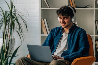 young man at home with laptop and headphones