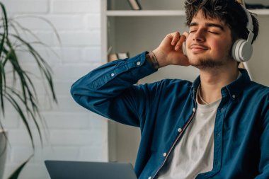 young man at home with laptop and headphones