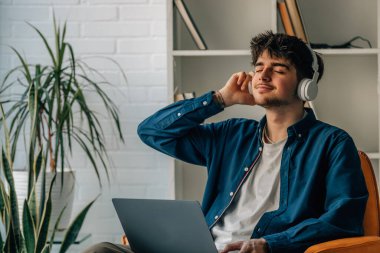 young man at home with laptop and headphones