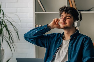 young man at home with laptop and headphones