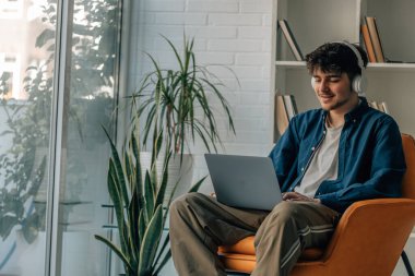 young man at home with laptop and headphones