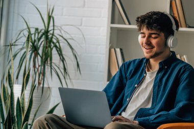 young man at home with laptop and headphones