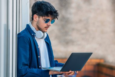 young man with laptop and sunglasses in the street