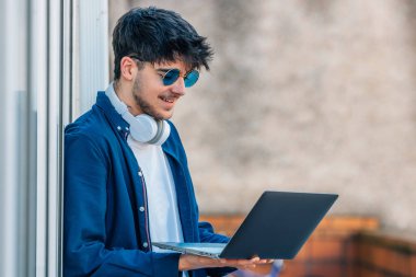 young man with laptop and sunglasses in the street