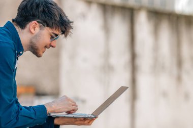 Sokakta dizüstü bilgisayarı olan genç bir adam.