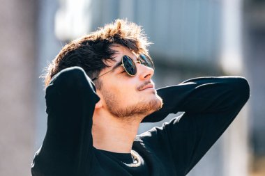 Sokaktaki genç adam dinleniyor, güneşleniyor.