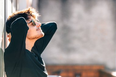 Şehirde güneşlenen rahat genç bir adam.