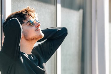 Şehirde güneşlenen rahat genç bir adam.