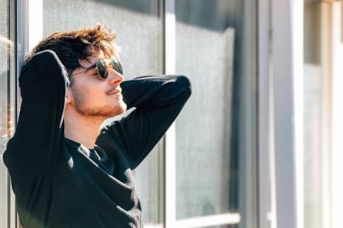 Şehirde güneşlenen rahat genç bir adam.