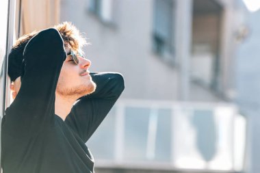 Şehirde güneşlenen rahat genç bir adam.