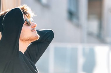 Şehirde güneşlenen rahat genç bir adam.