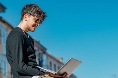Sokakta dizüstü bilgisayarı olan genç bir adam.