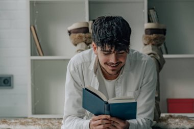 Evde kitap okuyan ya da okuyan rahat genç bir adam.