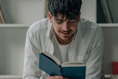 Evde kitap okuyan ya da okuyan rahat genç bir adam.