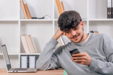 Öğrenci cep telefonu ya da akıllı telefona bakıyor