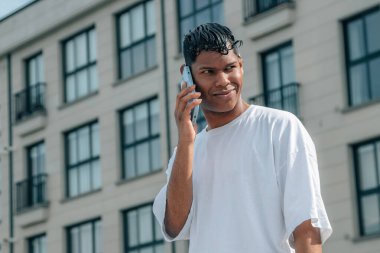 Şehir caddesinde cep telefonu olan genç bir Latin.