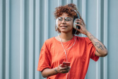 Kulaklık, cep telefonu ya da akıllı telefonu olan bir kız.