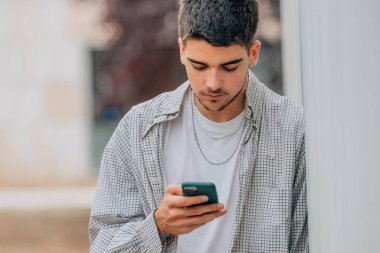 Sokaktaki genç çocuk cep telefonuna bakıyor.