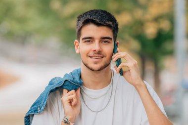 Sokaktaki genç adam cep telefonu ya da akıllı telefonuyla konuşuyor.